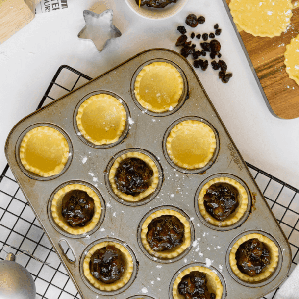 A muffin tray with fruit mince pie pastry and filling ready to go in the oven to bake 