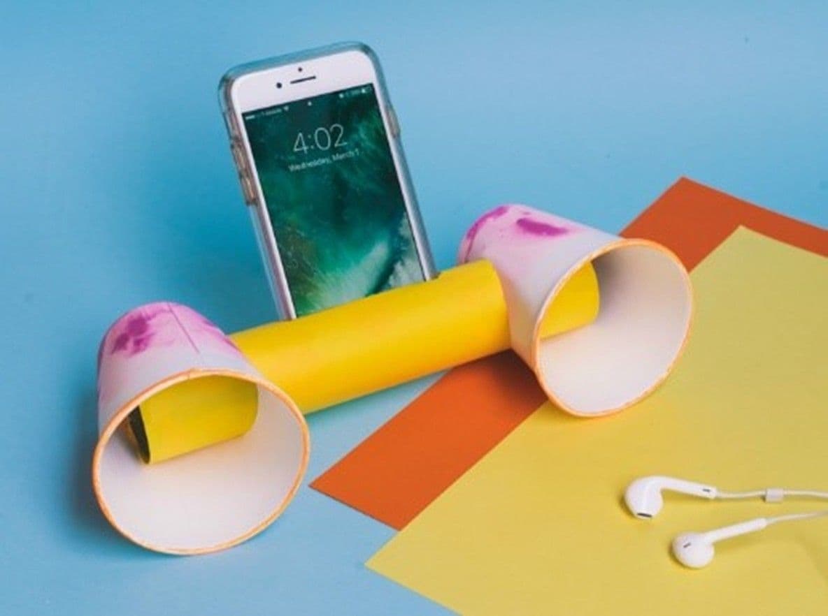 Two paper cups connected with a paper towel roll in the middle to make a phone holder and speakers