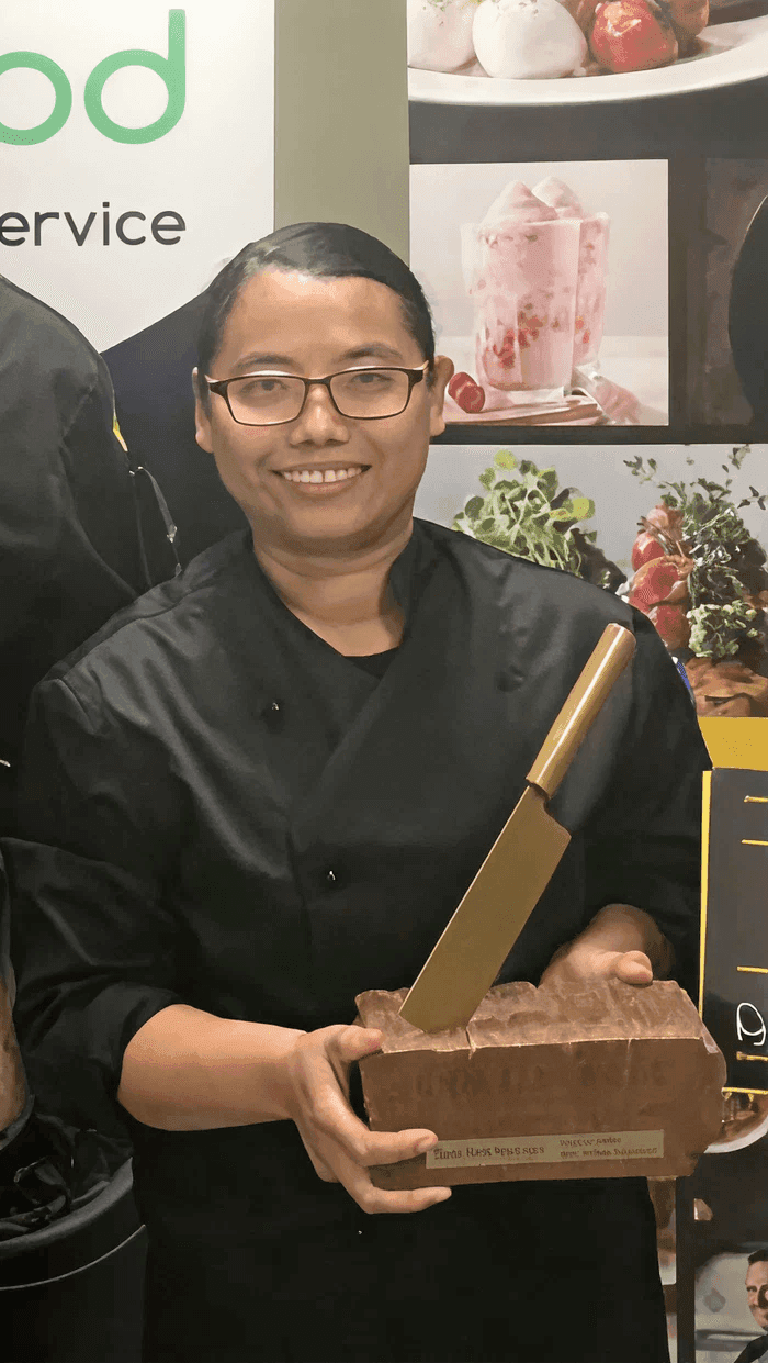 Chef smiling at the camera while holding a trophy